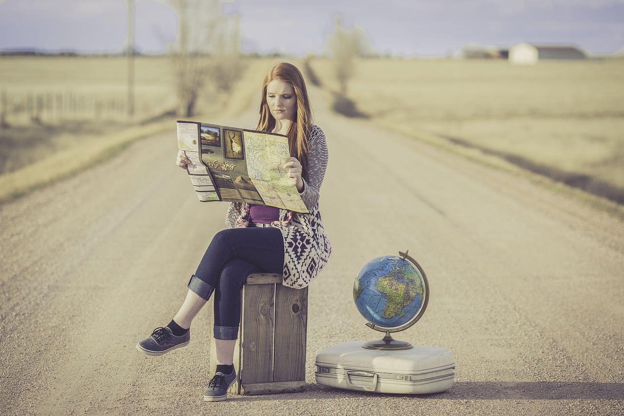 femme lisant carte du monde, qui prépare un voyage.